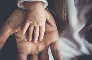 A child's hand on top of a father's hand