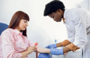 A phlebotomist draws blood from a patient in her home