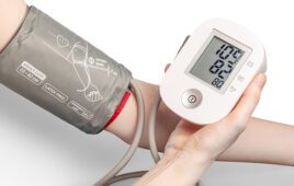 A patient holding a blood pressure monitor cuff on their arm
