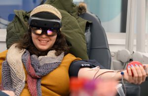 A woman wearing mixed reality goggles while donating blood