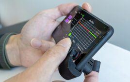 A finger on a plastic device that clips onto a smartphone to take blood pressure readings.