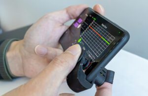 A finger on a plastic device that clips onto a smartphone to take blood pressure readings.