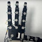 A photo of a robotic hand with touch sensors on its palm and four fingers.