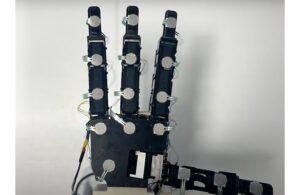 A photo of a robotic hand with touch sensors on its palm and four fingers.
