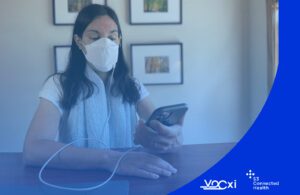 This Vocxi Health marketing image shows a woman at a table using the company's smart BreathEZ device for lung cancer detection.