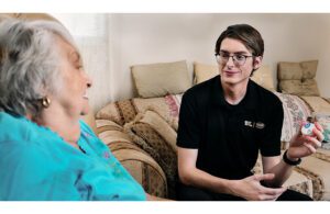 A photo of a Best Buy Geek Squad employee helping a chronic care patient with a remote monitoring device.